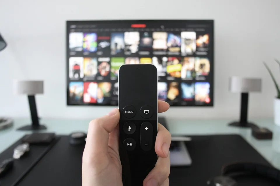 소파 앞 테이블 위에 놓인 TV 리모컨과 거실 텔레비전 화면